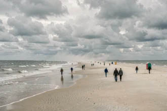 Vue panoramique d'une grande plage du nord de la France sous un ciel nuageux, avec une étendue de sable pâle et la mer du Nord en arrière-plan